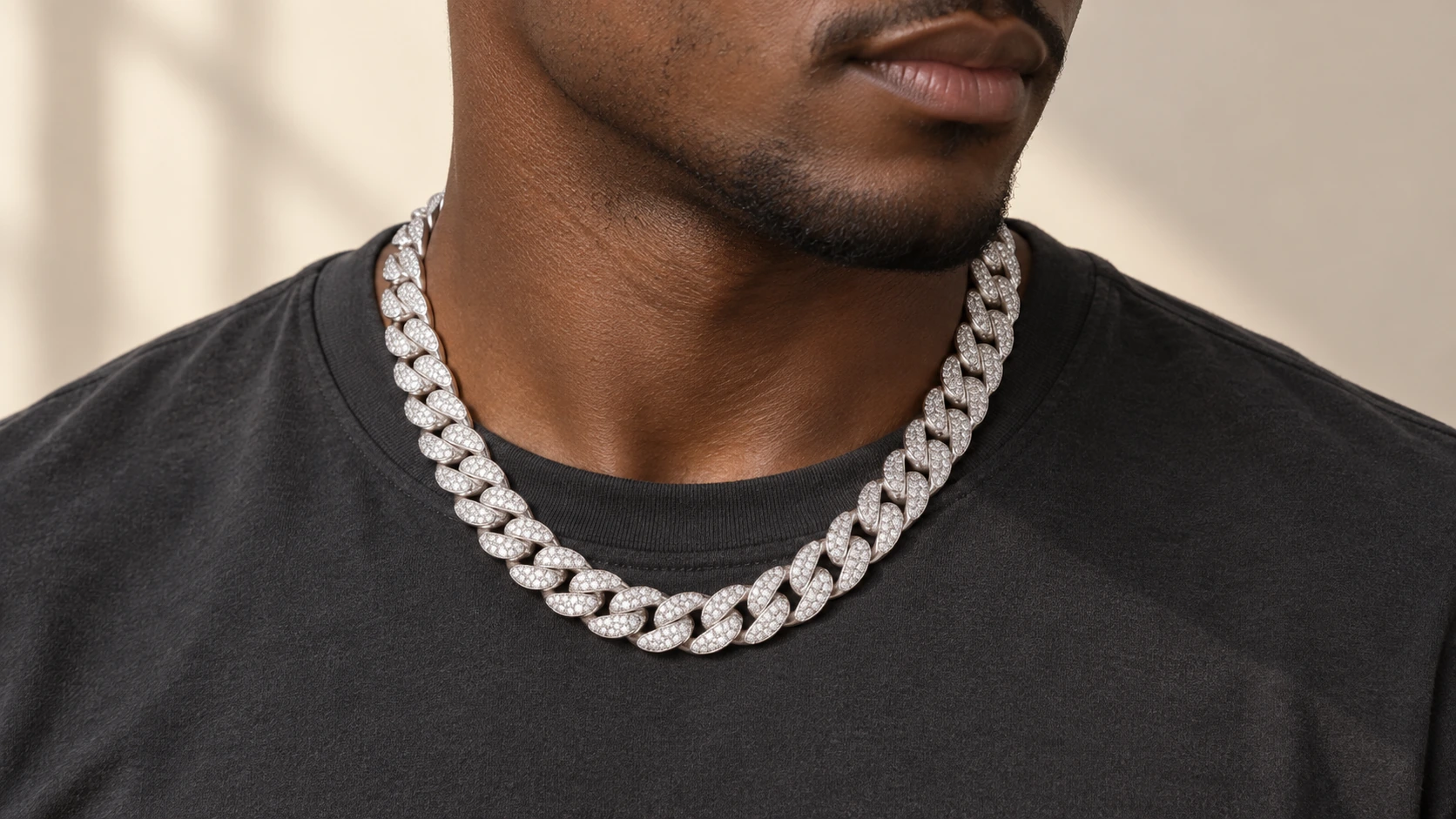 Man met een zilverkleurige Iced Out Cuban Ketting bij een donker shirt.