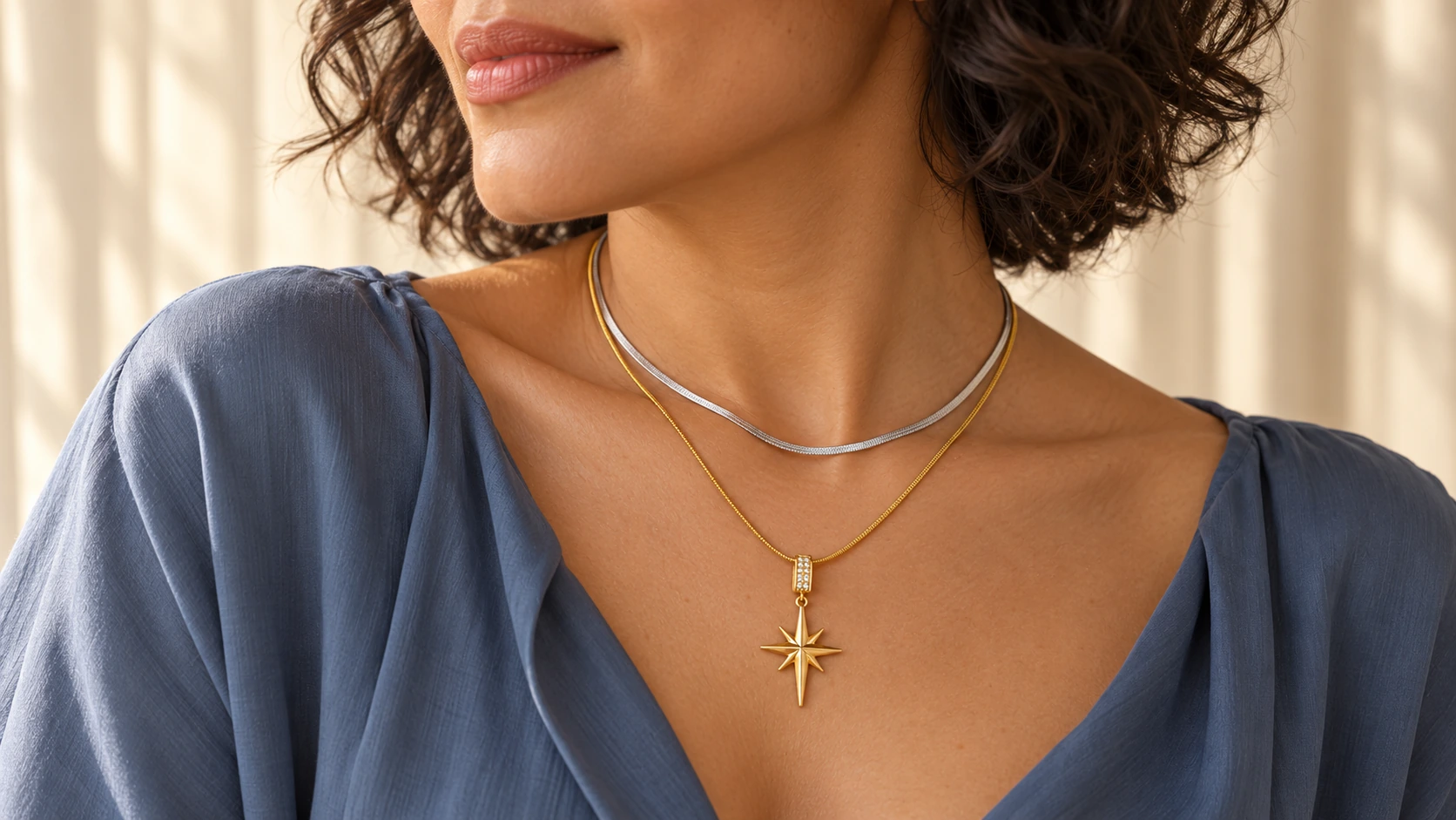 Zilveren Snake Ketting gecombineerd met een gouden Nova Ketting bij een blauwe top.
